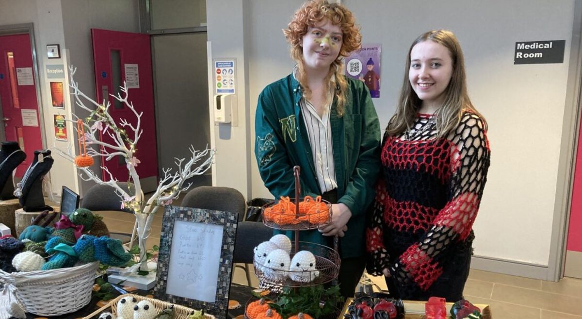 Picture of two students smiling while standing behind their Halloween Market stall.